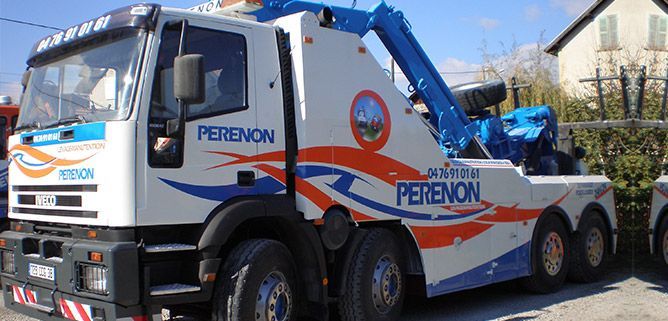 Camion de dépannage blanc et bleu avec des accents rouges stationné à l'extérieur, portant l'inscription PERENON.