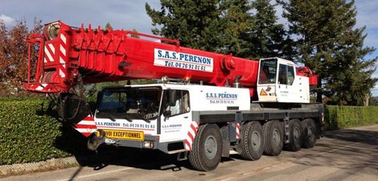 Camion-grue  stationné à l'extérieur, près d'une haie et d'arbres