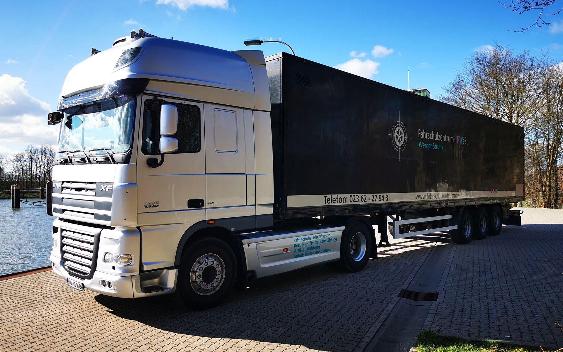 Ein großer weißer Lastwagen mit einem schwarzen Anhänger steht auf einem Parkplatz.