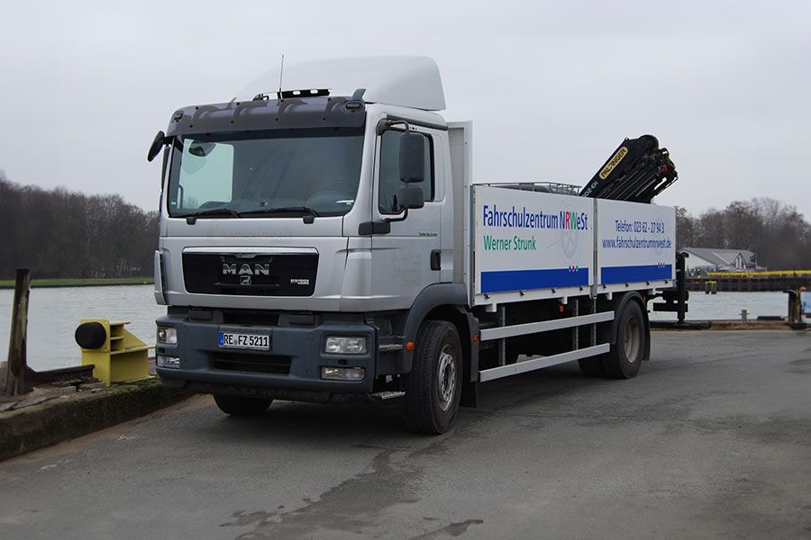 Ein MAN-LKW ist vor einem Gewässer geparkt.