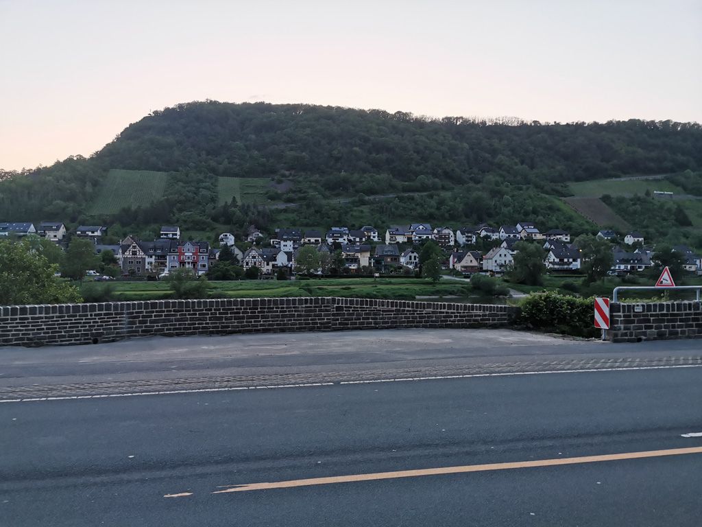 Eine Straße mit einem Berg im Hintergrund und einer Backsteinmauer im Vordergrund