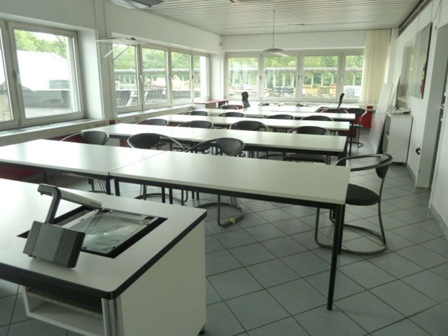 Ein Klassenzimmer mit Tischen und Stühlen und einem Podium