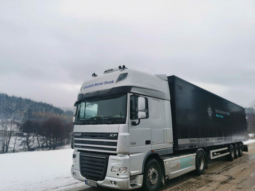 Ein Sattelschlepper steht im Schnee am Straßenrand.