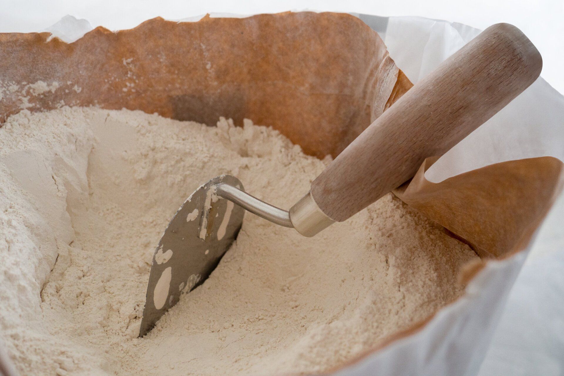 Eine Kelle ragt aus einem Sack Zement