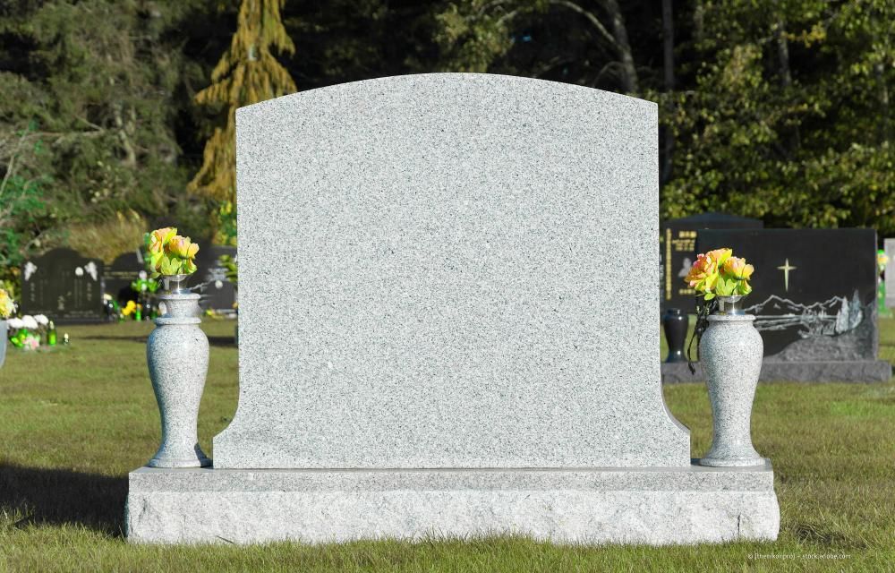 Ein leerer Grabstein mit zwei Blumenvasen auf einem Friedhof