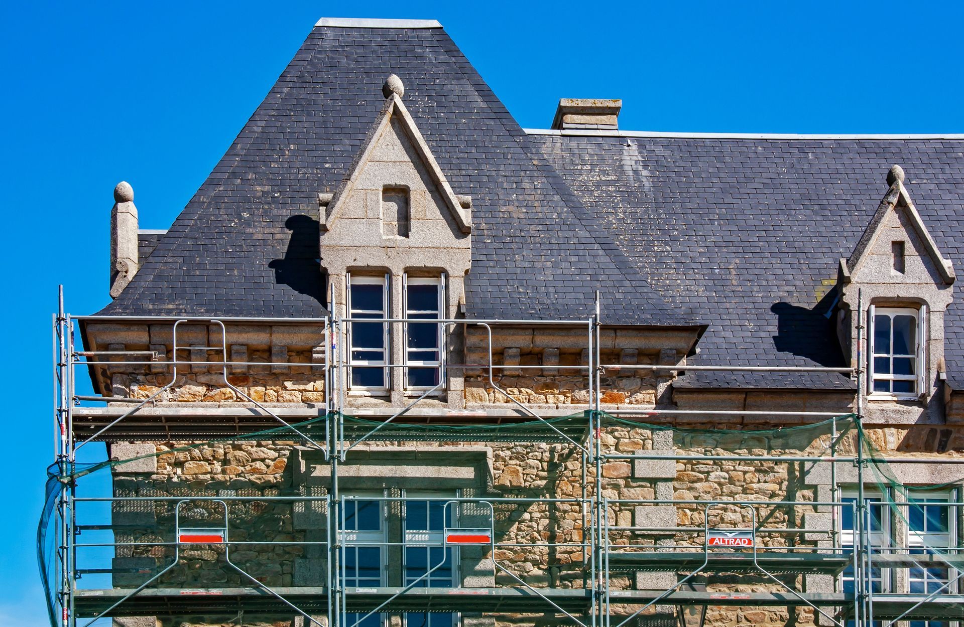 Façade d'une maison en pierre en cours de rénovation avec échafaudage installé