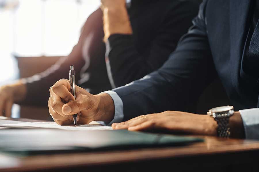 Un avocat avec une montre écrit sur une feuille avec un stylo