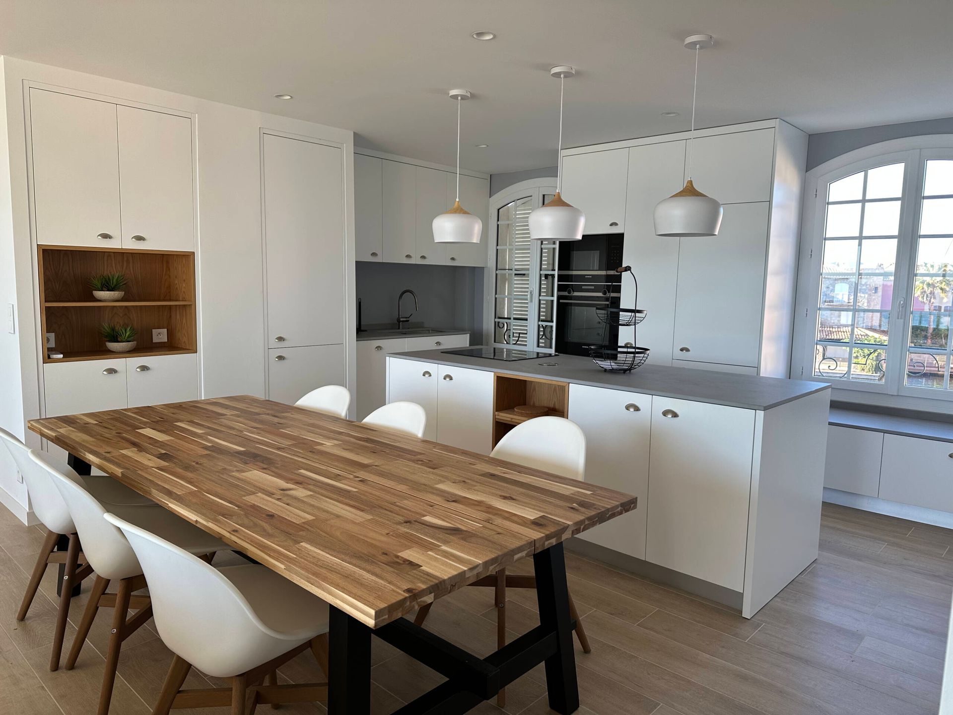 Une cuisine avec une table en bois et des chaises blanches