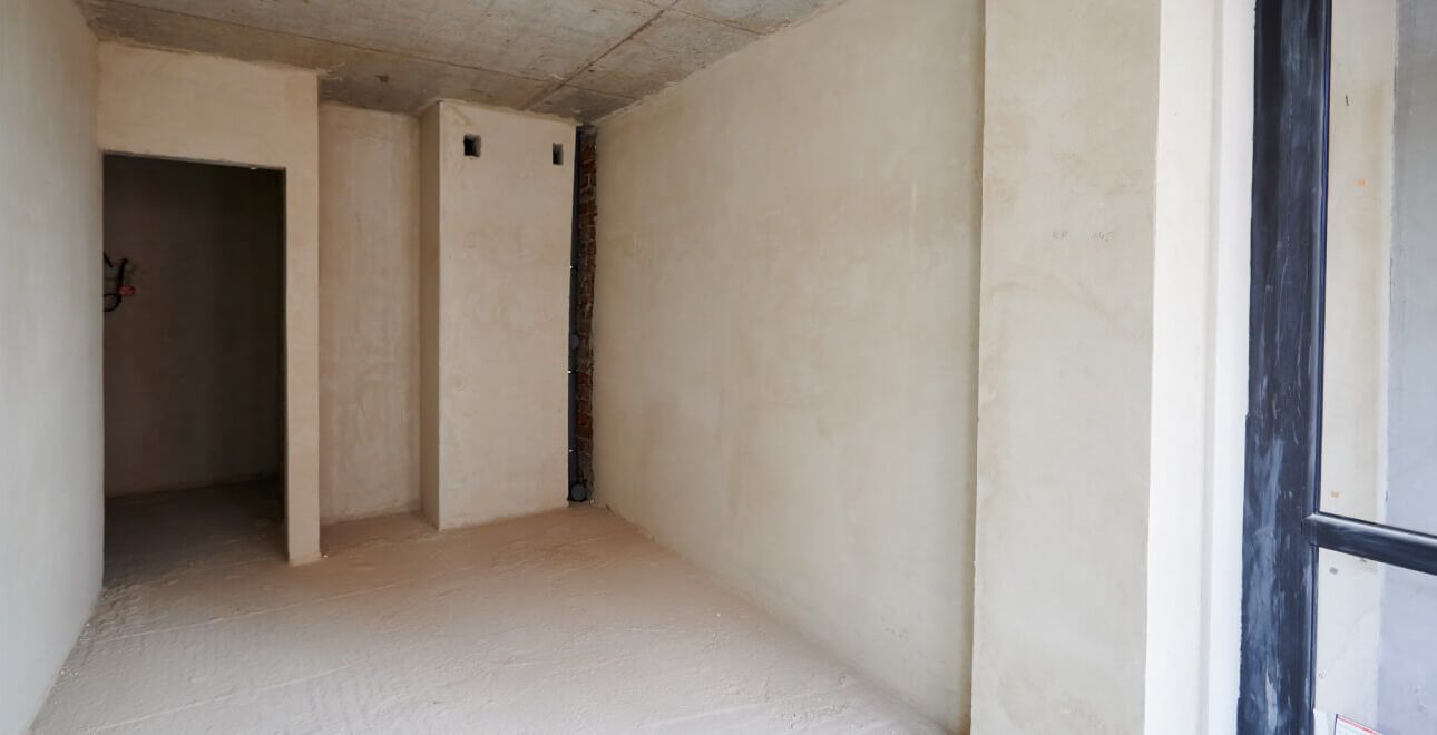 Une pièce vide avec des murs blancs et une porte dans un bâtiment en construction.