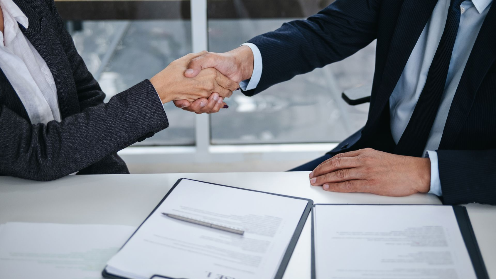 Une personne en costume serrant la main pour conclure un contrat.