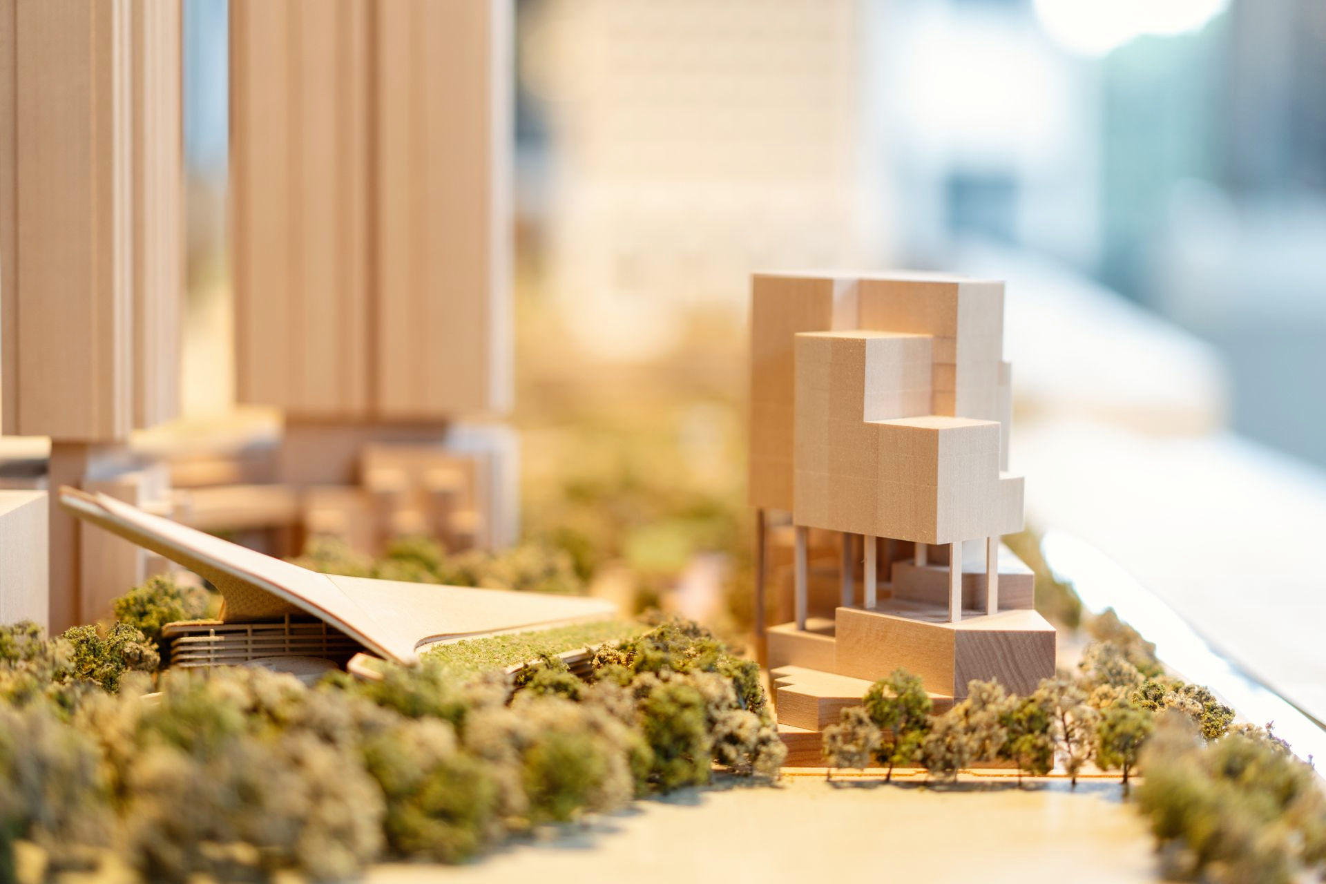 Une maquette architecturale miniature représentant des structures en bois, des bâtiments et de petits arbres sur une surface paysagée.