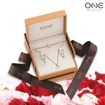 Um conjunto de colar e brinco em uma caixa cercada por pétalas de rosa.