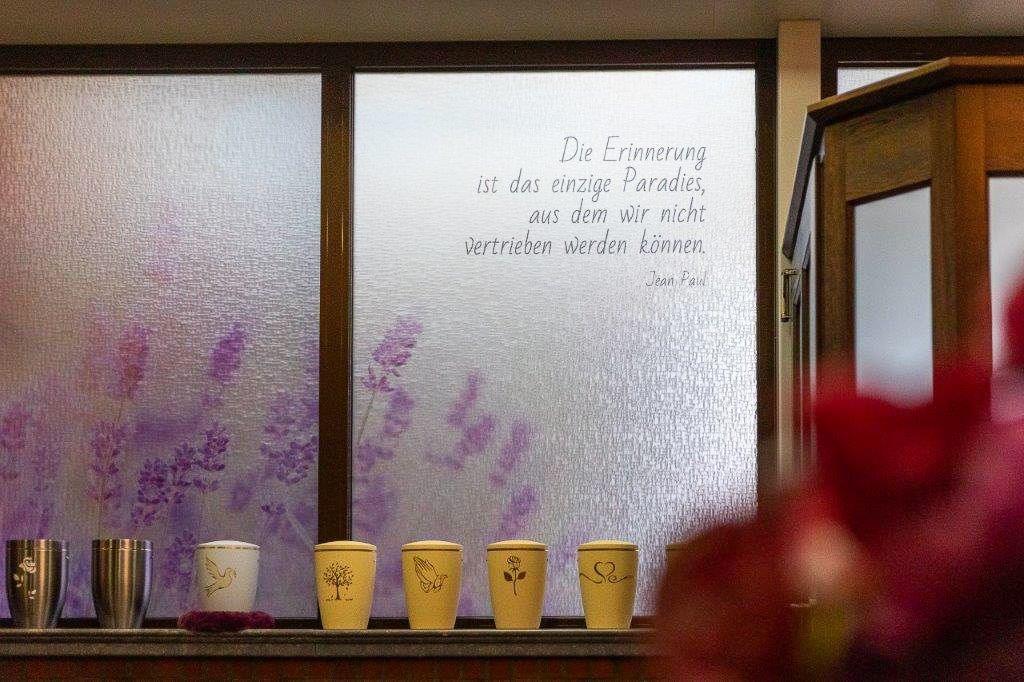 eine Reihe von Tassen , die auf einem Regal neben einem Fenster stehen - Bestattungen Vornholt in Borken-Burlo