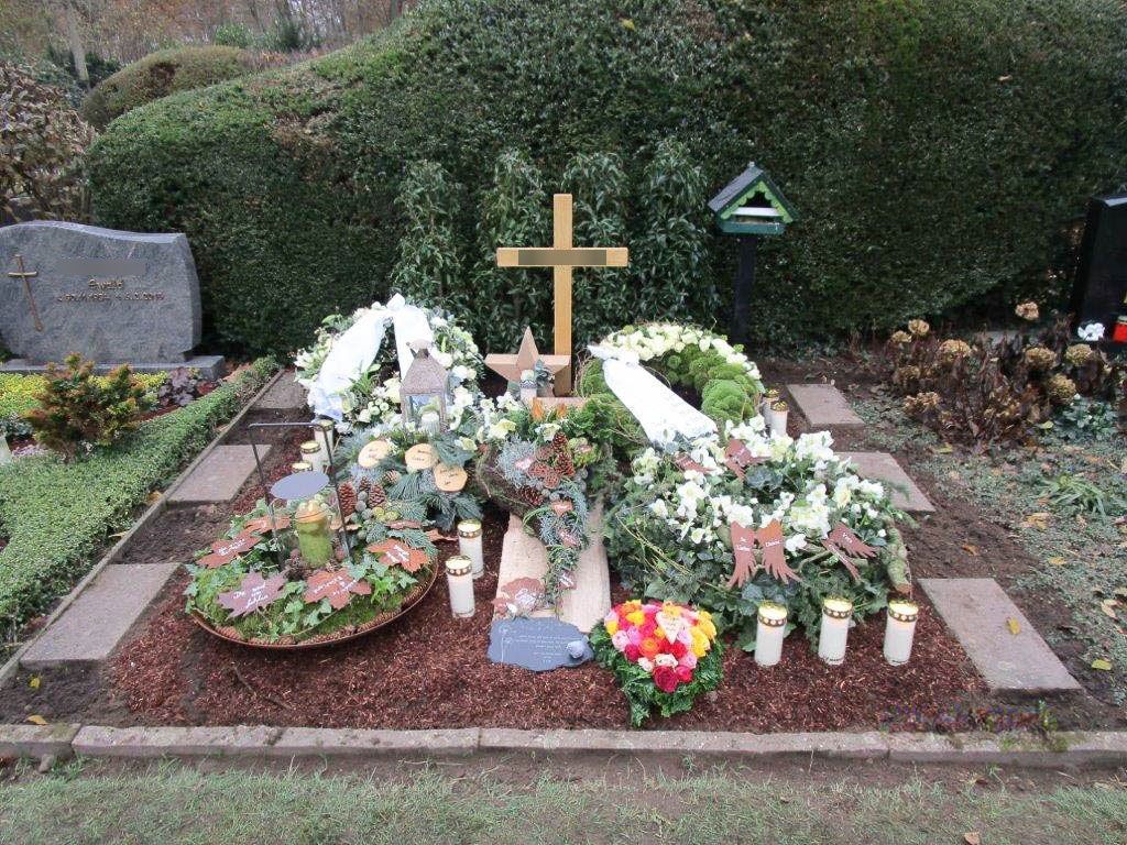ein Grab mit Blumen und Kerzen und einem Holzkreuz - Bestattungen Vornholt in Borken-Burlo