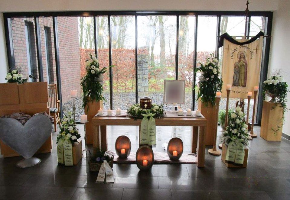 ein Tisch mit Kerzen und Blumen in einem Raum mit vielen Fenstern - Bestattungen Vornholt in Borken-Burlo