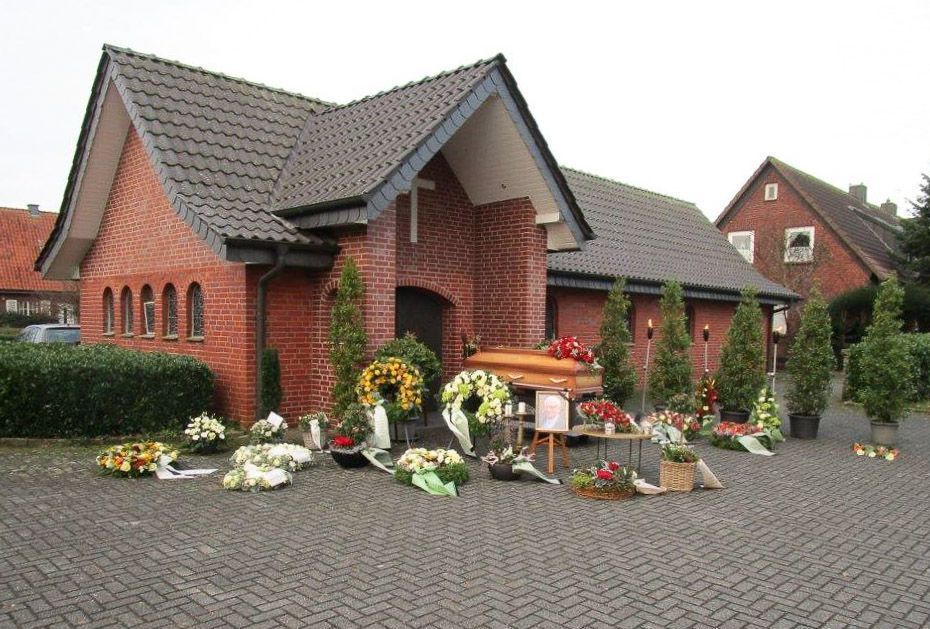 ein rotes Backsteingebäude mit einem Sarg davor - Bestattungen Vornholt in Borken-Burlo