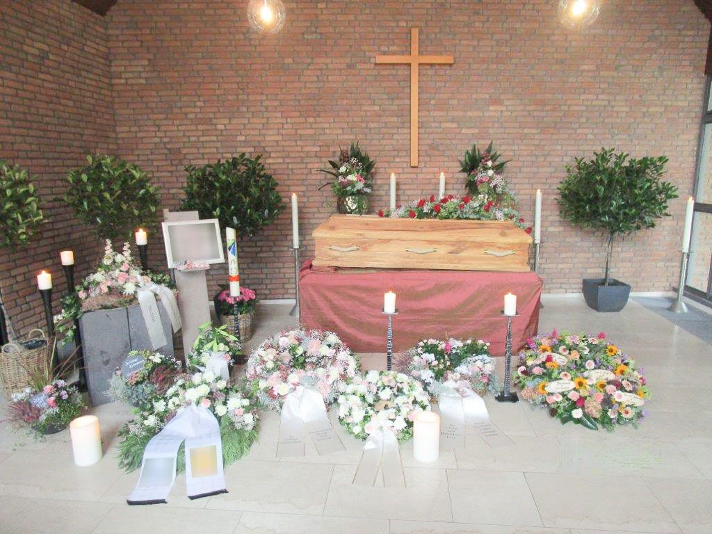 ein sarg steht auf einem tisch in einer kirche mit blumen und kerzen - Bestattungen Vornholt in Borken-Burlo