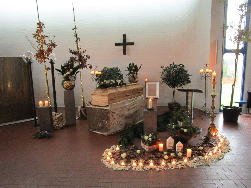 ein Raum mit einem Sarg und Kerzen und einem Kreuz an der Wand - Bestattungen Vornholt in Borken-Burlo