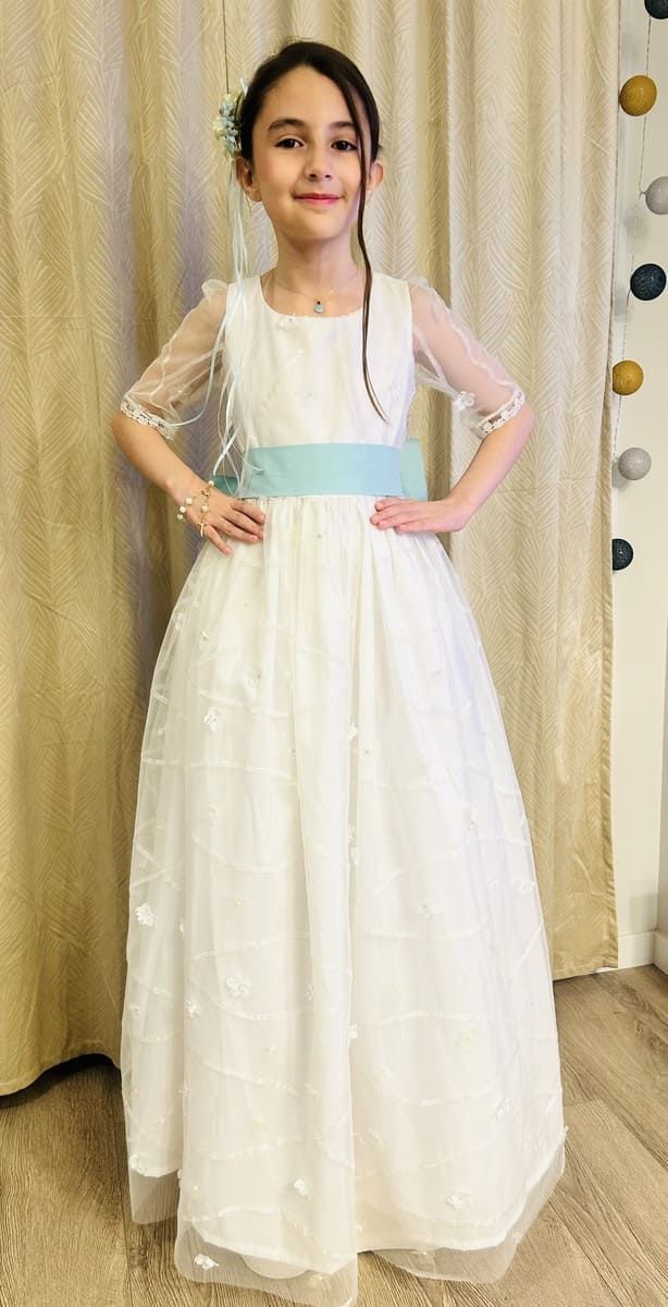 Un vestido de novia está sobre un maniquí delante de rollos de tela.