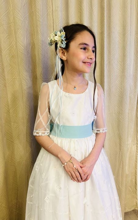 Un vestido blanco cuelga de una percha delante de una cortina morada.