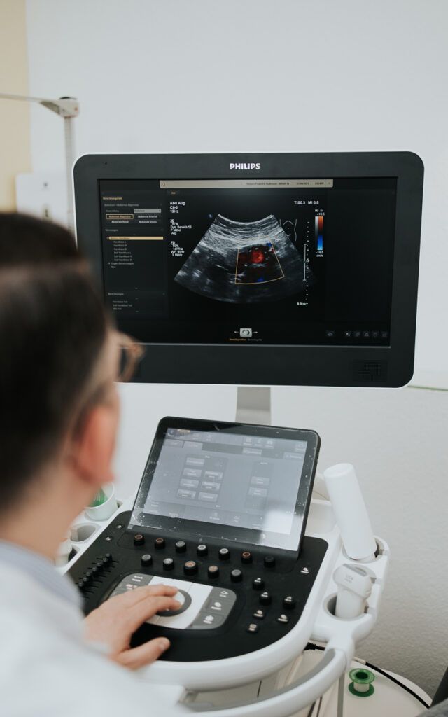 Ultraschalluntersuchung im Gange, Sonogramm auf dem Monitor und Arzt bedient die Konsole.