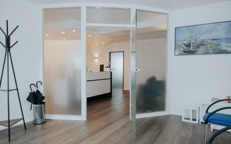 Helle, moderne Bürolobby mit Glastüren, Holzboden, Garderobe und Wandkunst