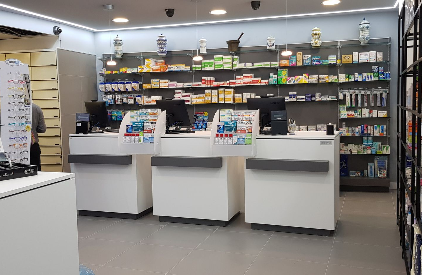 Farmacista sorridente, con in mano un blocco per appunti, in una corsia della farmacia, circondato da scaffali pieni di prodotti.