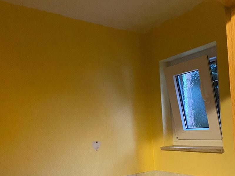 Ein Raum mit gelben Wänden und einem weißen Fenster.