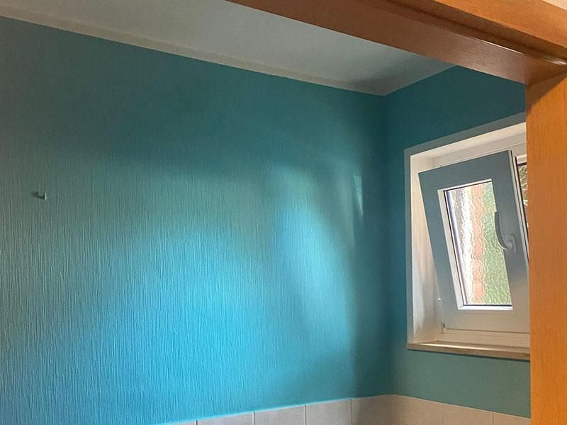 Ein Badezimmer mit blauen Wänden und einem Fenster.