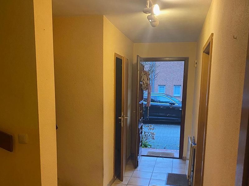 Ein Flur mit einer offenen Tür und einem im Hintergrund geparkten Auto.