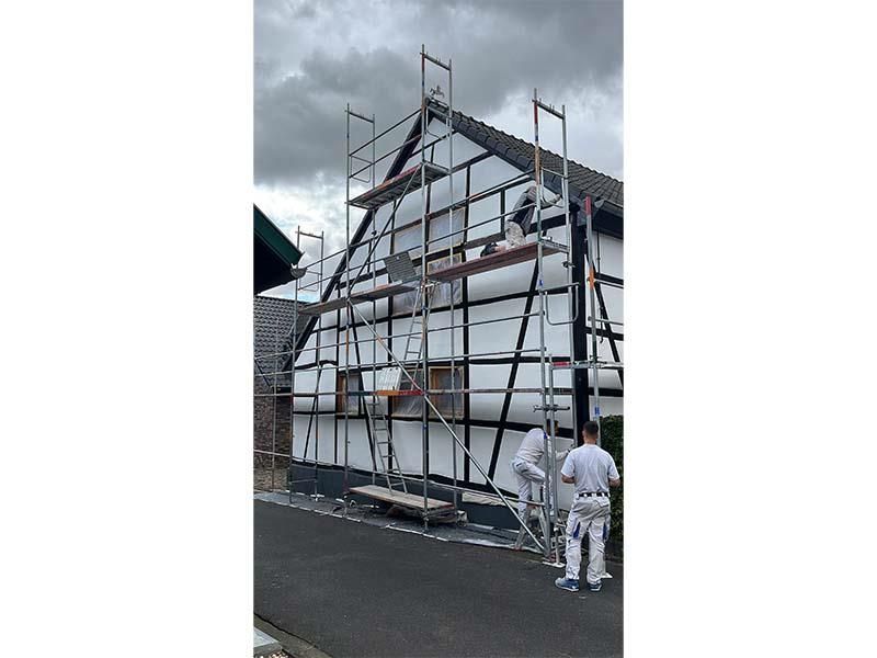 Eine Gruppe von Menschen steht vor einem Gebäude mit Gerüst.