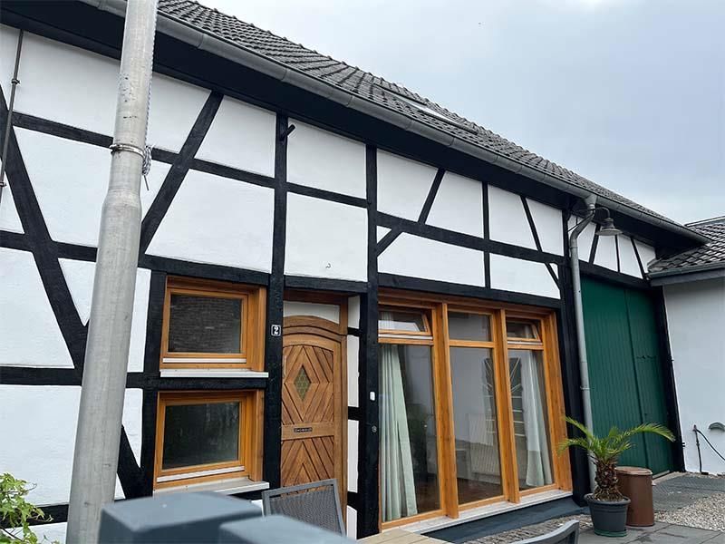 Ein weiß-schwarzes Haus mit einer grünen Tür und grünen Fenstern.