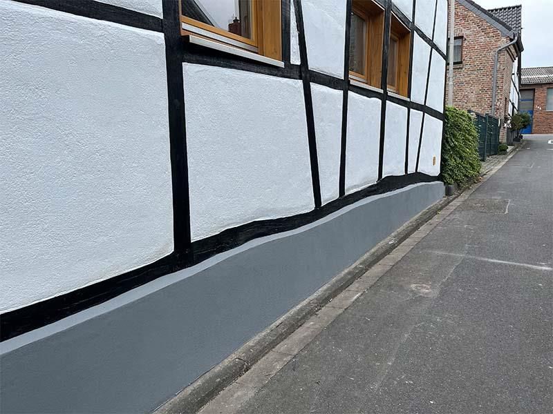 Am Straßenrand steht ein weißes Gebäude mit schwarzen Verzierungen.