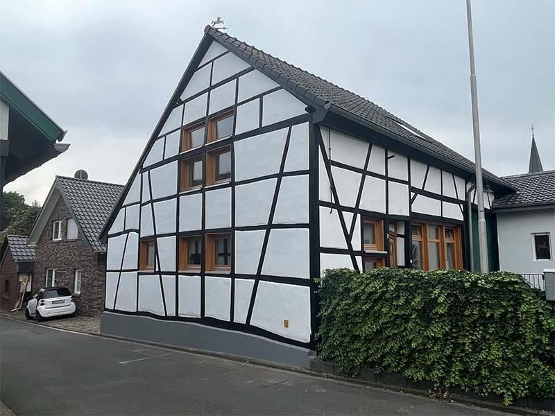 Ein weiß-schwarzes Haus mit einem davor geparkten Auto.