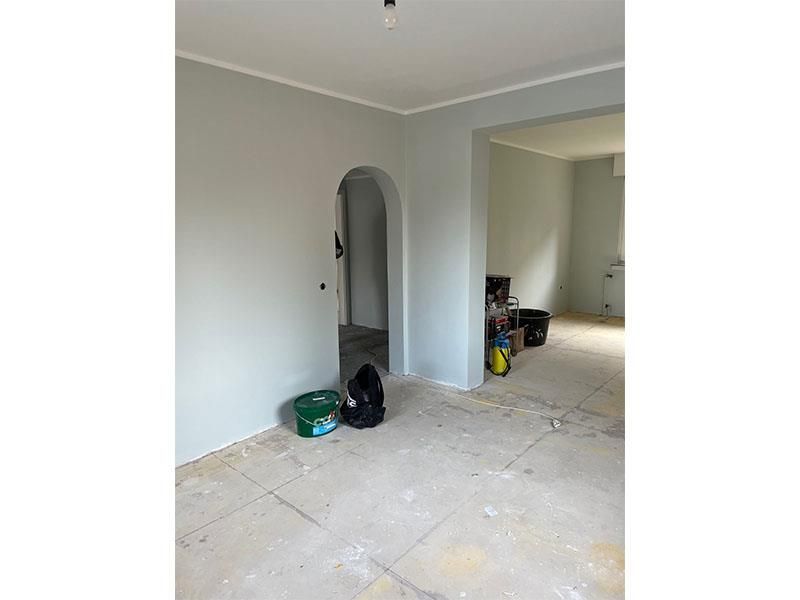 Ein Raum mit einer Tür und einem Eimer Farbe auf dem Boden.