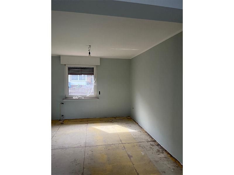 Ein leerer Raum mit einem Fenster und einem Holzboden.