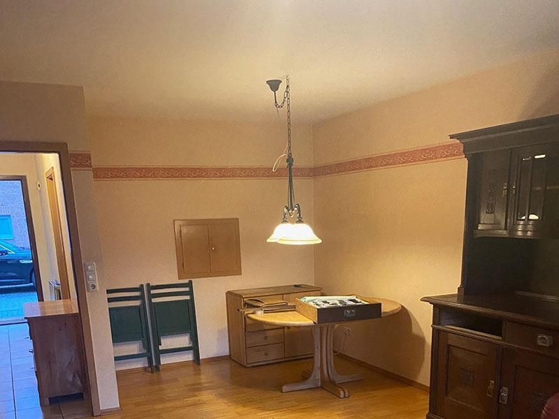 Ein Wohnzimmer mit einem Tisch und Stühlen und einer Lampe, die von der Decke hängt.