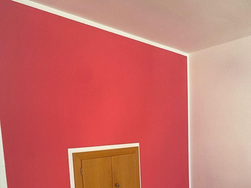 Ein Raum mit roten Wänden und weißen Zierleisten und einer Tür