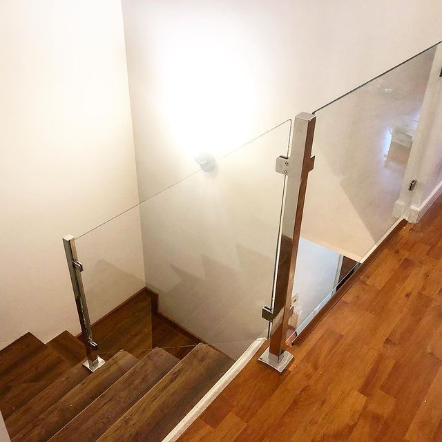 Una escalera con escalones de madera y barandilla de cristal.