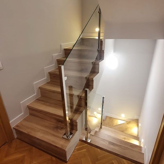 Una escalera con escalones de madera y barandilla de cristal.