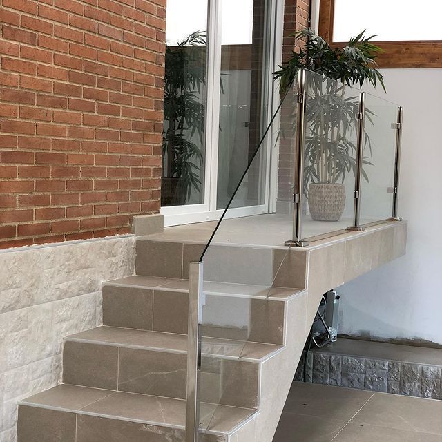 Un conjunto de escaleras que conducen a un balcón con barandilla de vidrio.