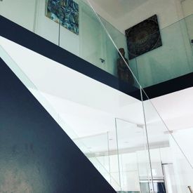 Una escalera con barandilla de cristal y una estatua en la pared.