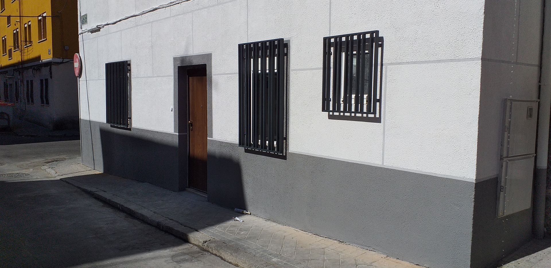 Un edificio blanco y gris con dos ventanas y una puerta.