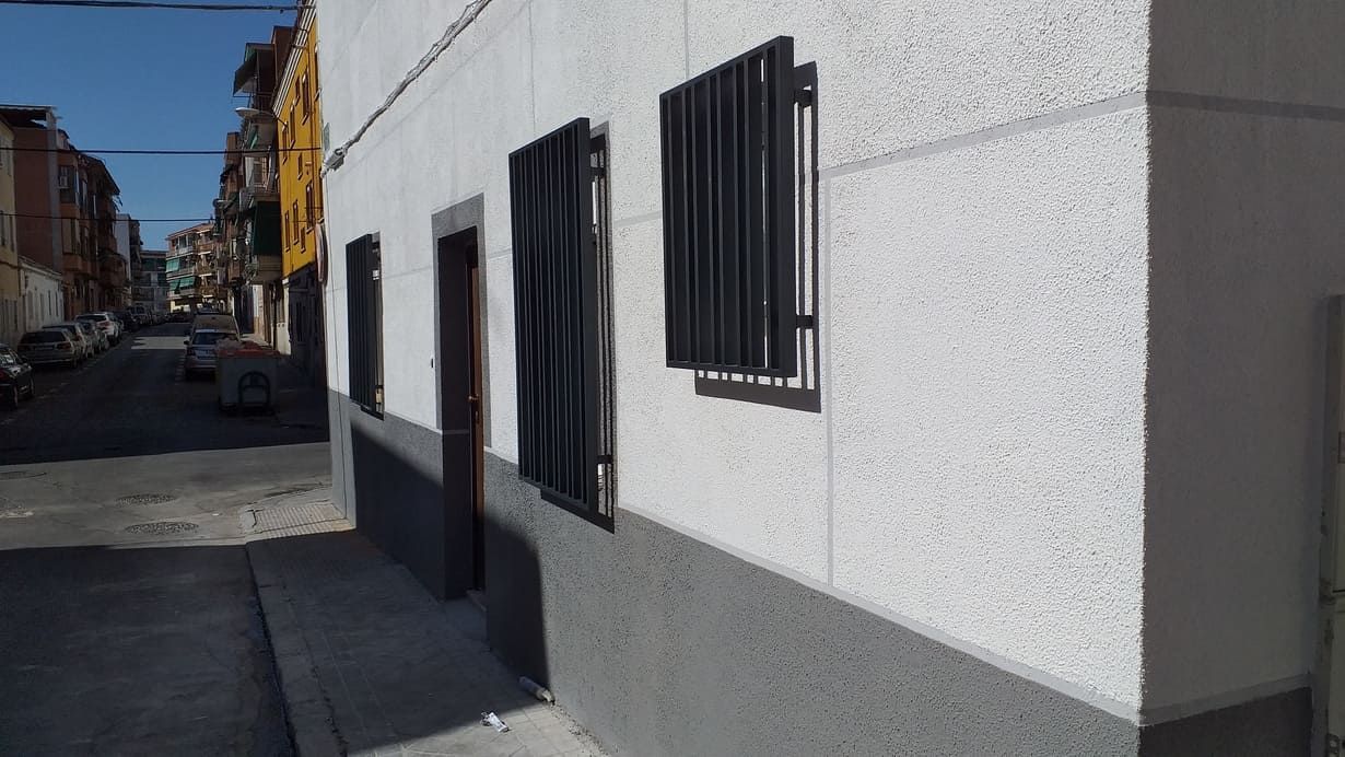 Un edificio blanco con rejas negras en las ventanas