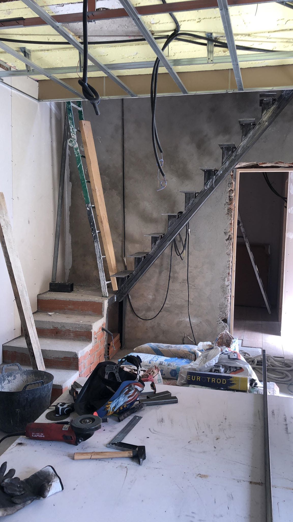 Se está construyendo una escalera en una habitación con muchas herramientas en el suelo.