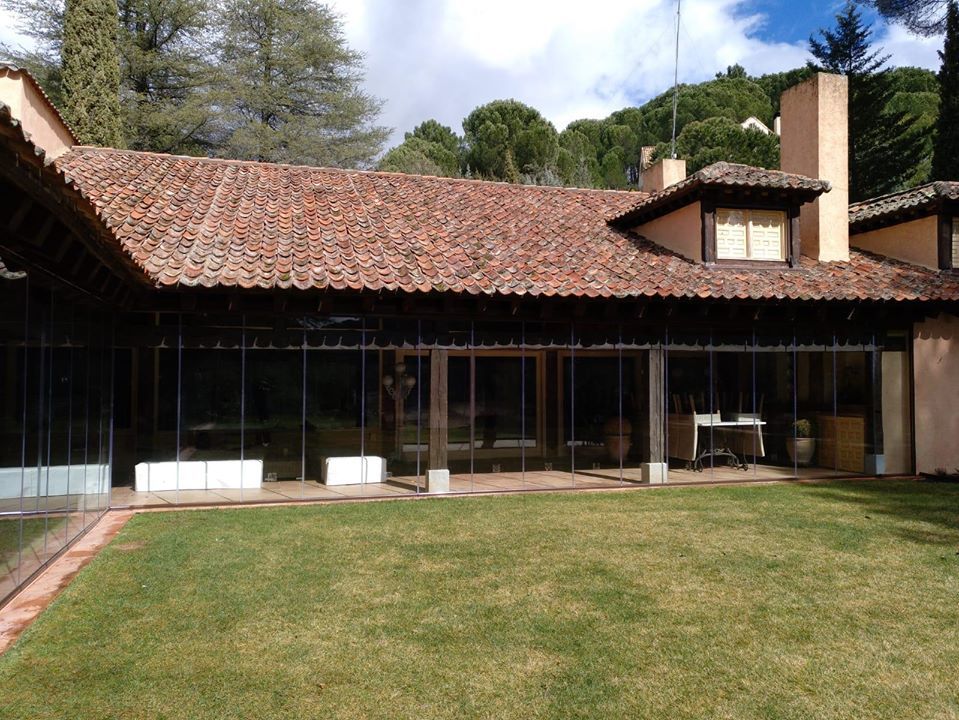Una casa grande con techo de tejas rojas y un amplio jardín delante de ella.