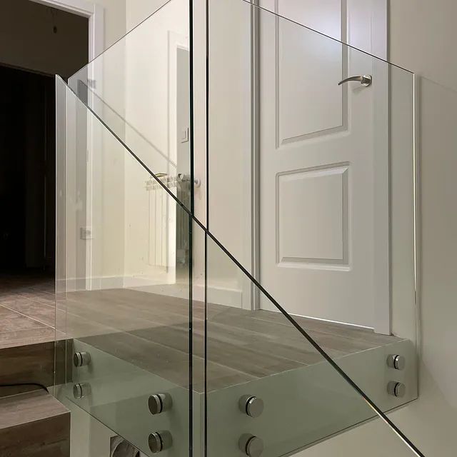 Una escalera con barandilla de cristal y escalones de madera.