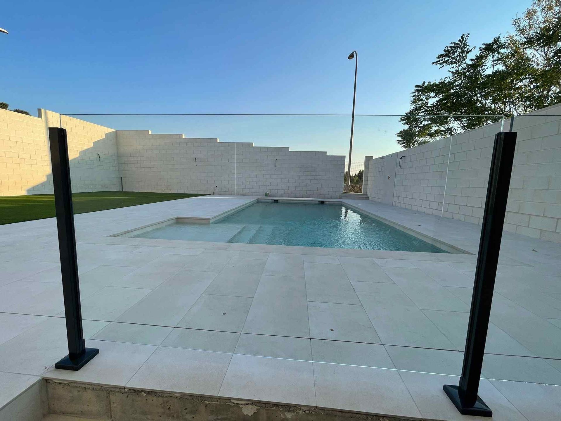 Una piscina con una valla de cristal a su alrededor.