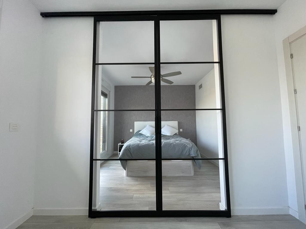 Un dormitorio con una puerta corrediza de vidrio que conduce a una cama.