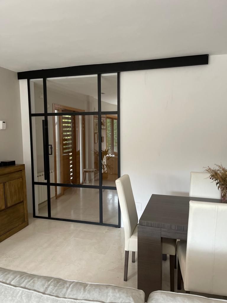 Una sala de estar con una mesa y sillas y una puerta corrediza de vidrio.